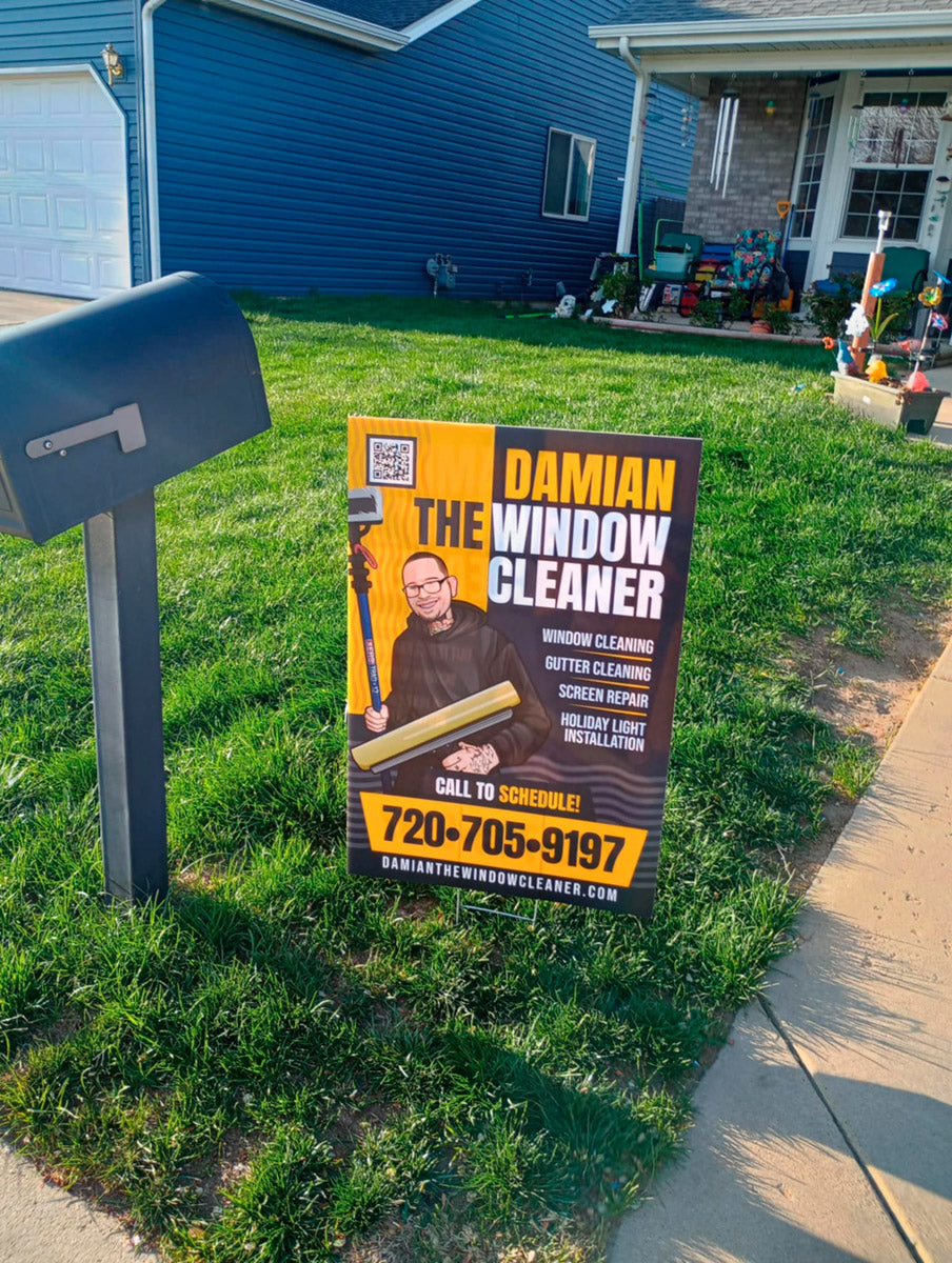 Damian The Window Cleaner yard sign displayed beside a residential mailbox with bold yellow and black design and service list, printed by WCR Marketing.