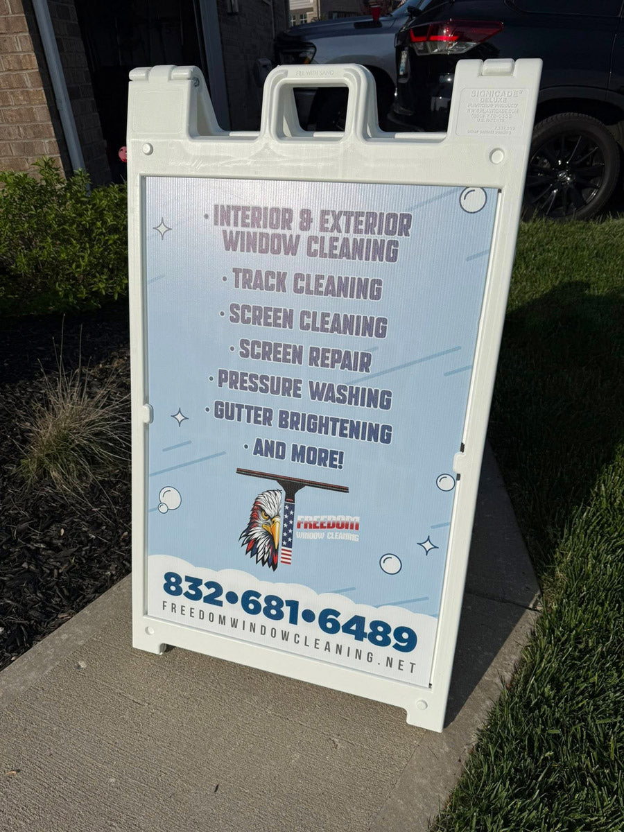 Freedom Window Cleaning A-frame sign listing services such as screen repair, gutter brightening, and pressure washing, displayed near driveway, printed by WCR Marketing.
