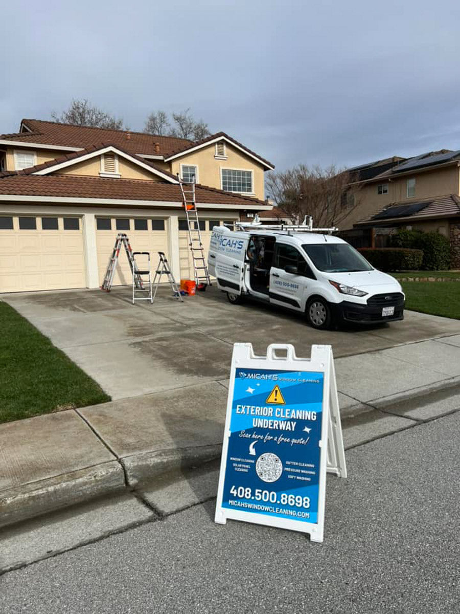 Micah’s Window Cleaning A-frame sign placed on residential driveway during service, showing exterior cleaning underway message, printed by WCR Marketing.