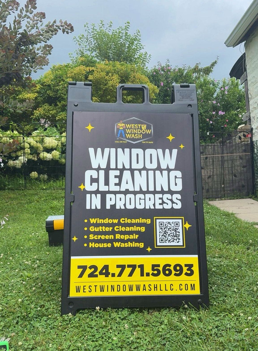 West Window Wash A-frame sign featuring bold black and yellow “Window Cleaning In Progress” design with QR code and service list, printed by WCR Marketing.