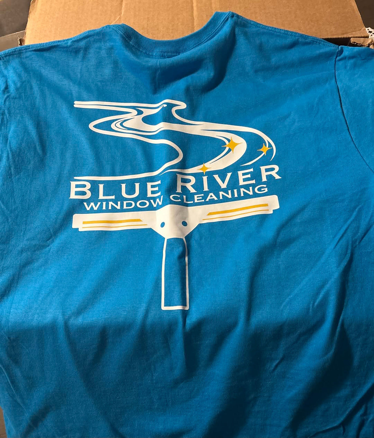 Blue River Window Cleaning short sleeve t-shirt featuring white squeegee and flowing river logo design printed on back, printed by WCR Marketing.