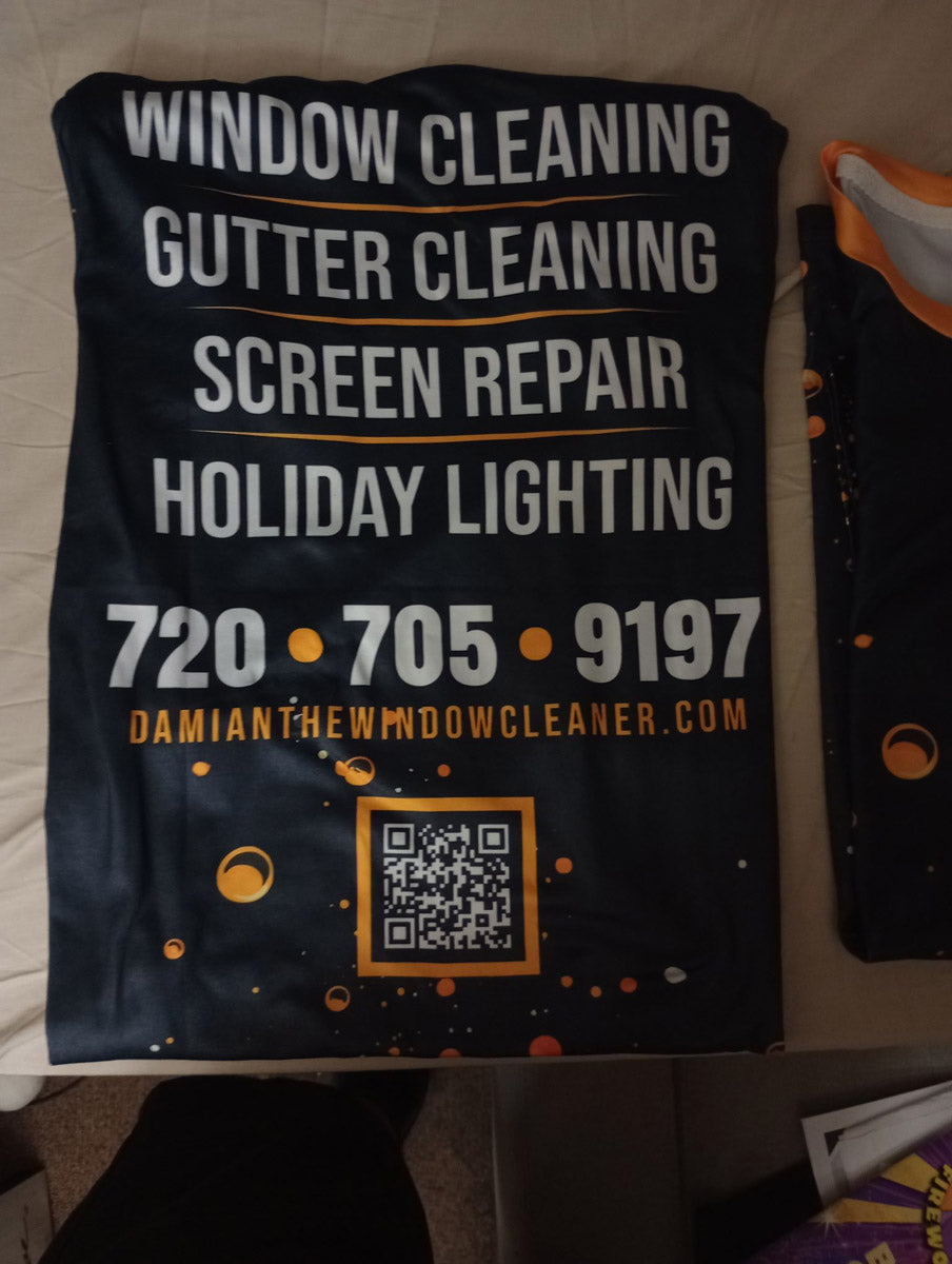 Closeup of the dye-sublimated jersey back panel showing services, QR code, and brand details for Damian The Window Cleaner, printed by WCR Marketing.