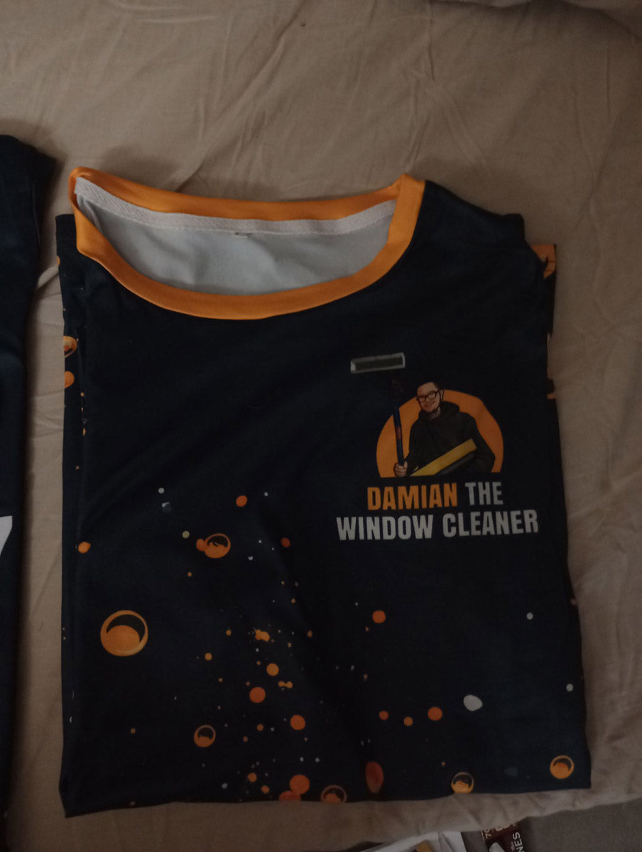 Folded front of Damian The Window Cleaner dye-sub jersey with circular logo and splatter graphic pattern, printed by WCR Marketing.