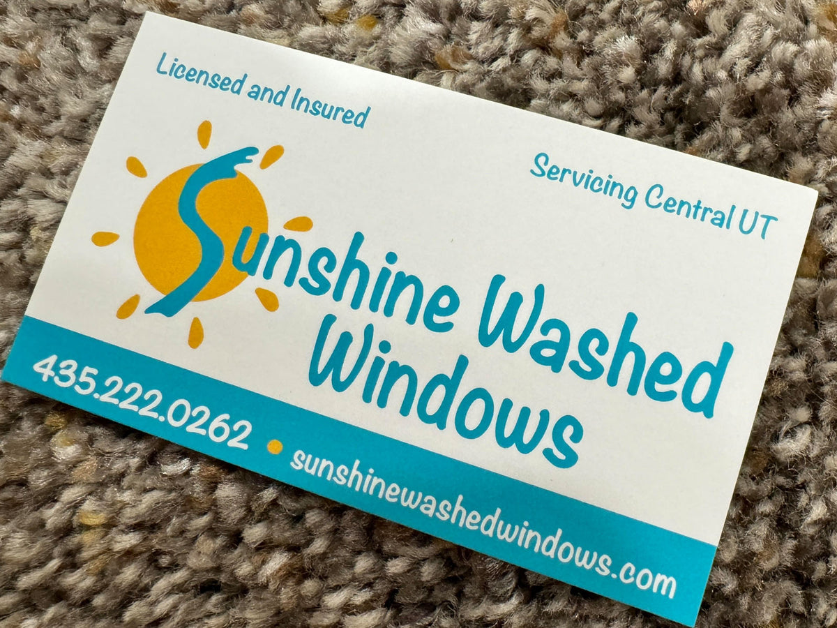 Sunshine Washed Windows business card front showing sun and squeegee logo with blue and yellow branding, printed by WCR Marketing.