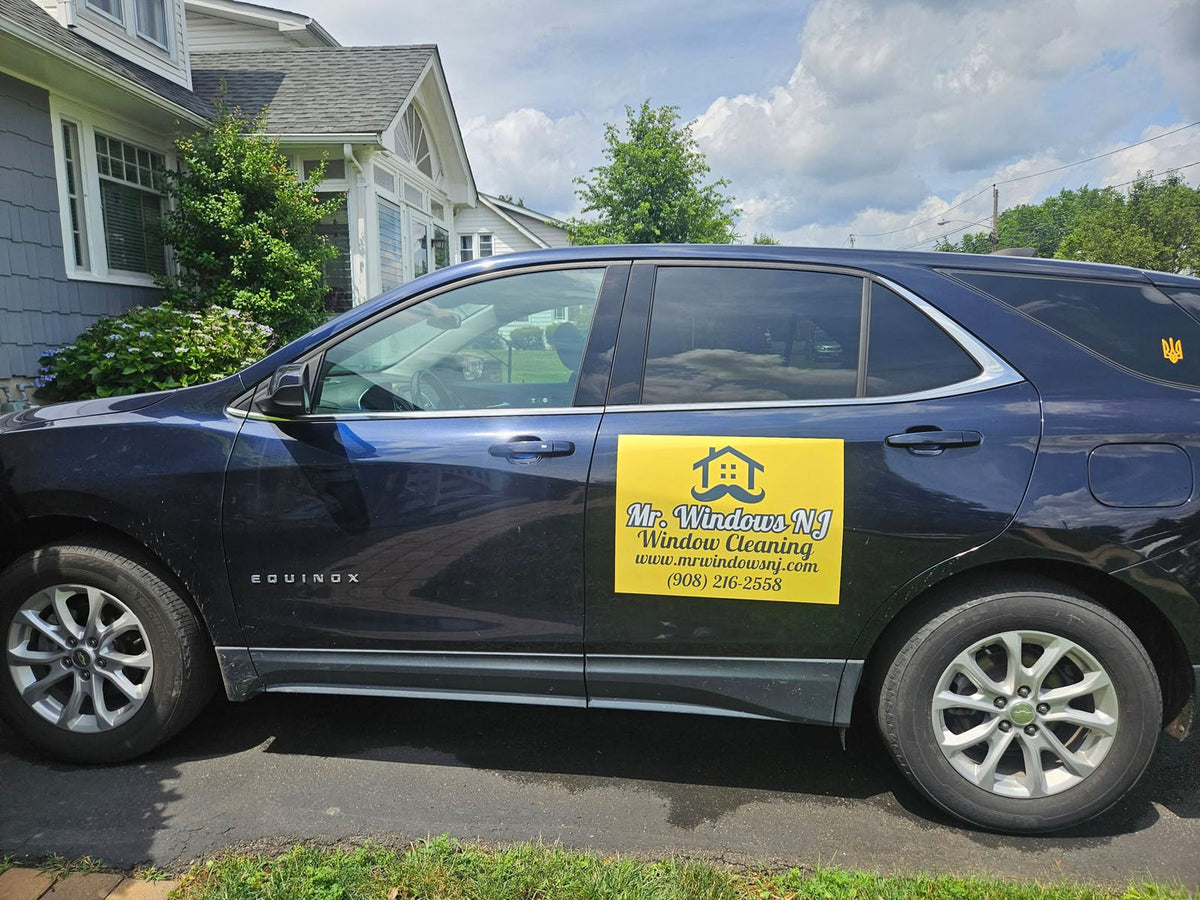 Dark blue SUV with a bright yellow Mr. Windows NJ Window Cleaning magnet parked in a suburban driveway, printed by WCR Marketing.