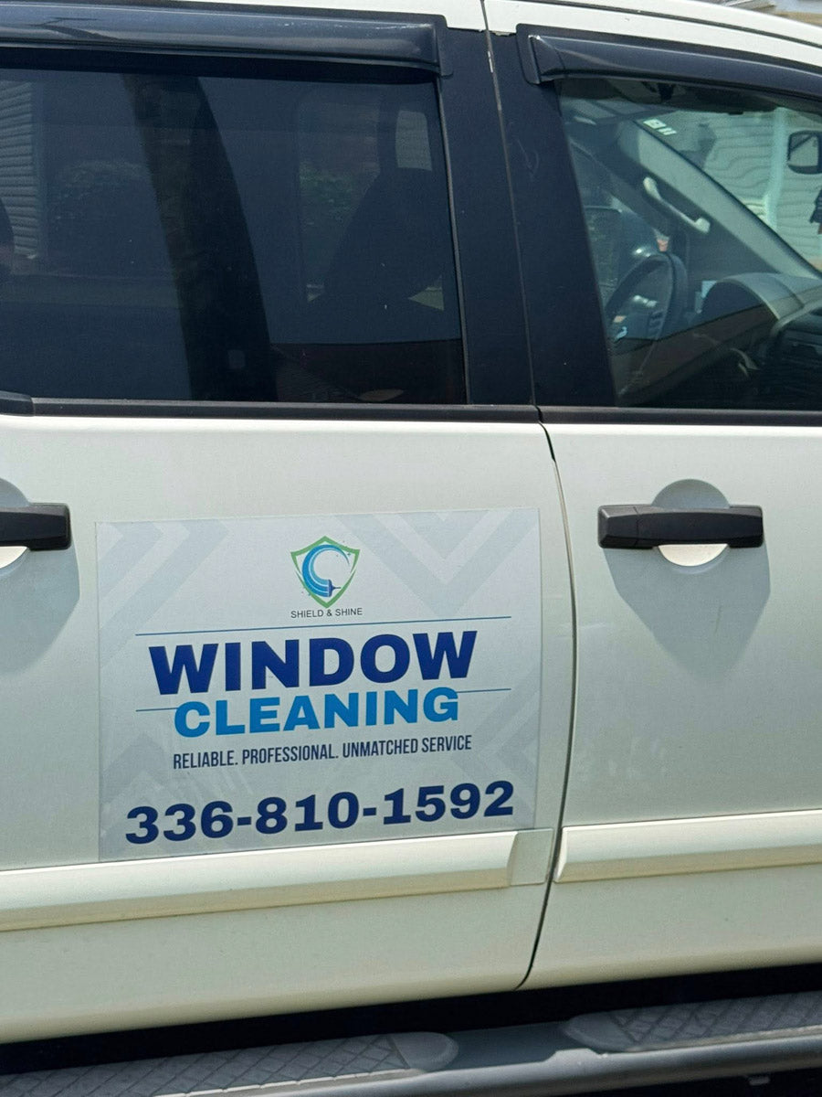 Closeup of a Shield & Shine Window Cleaning door magnet on a white work van with bold blue and teal branding, printed by WCR Marketing.
