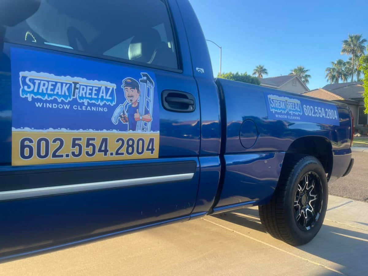 Blue pickup truck with a Streak Free AZ Window Cleaning door magnet parked in a sunny driveway, printed by WCR Marketing.