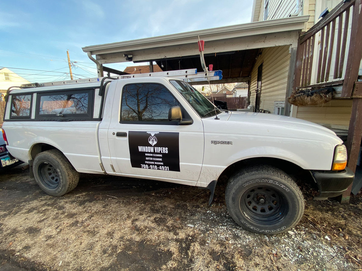 Window Vipers service truck with a black door magnet advertising window, gutter, and pressure cleaning parked beside a home, printed by WCR Marketing.