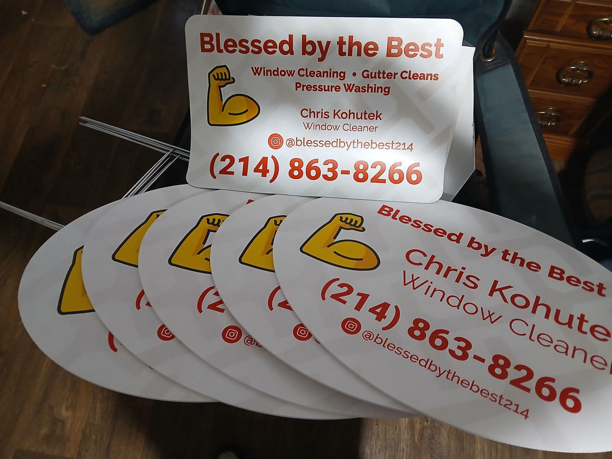 Blessed by the Best window cleaning yard signs with flexing arm icon stacked on a wood floor, printed by WCR Marketing.
