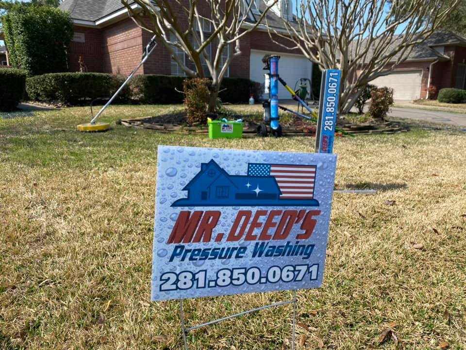 Yard sign for Mr. Deed’s Pressure Washing displayed on a residential lawn, featuring full-color house and flag graphic, printed by WCR Marketing.