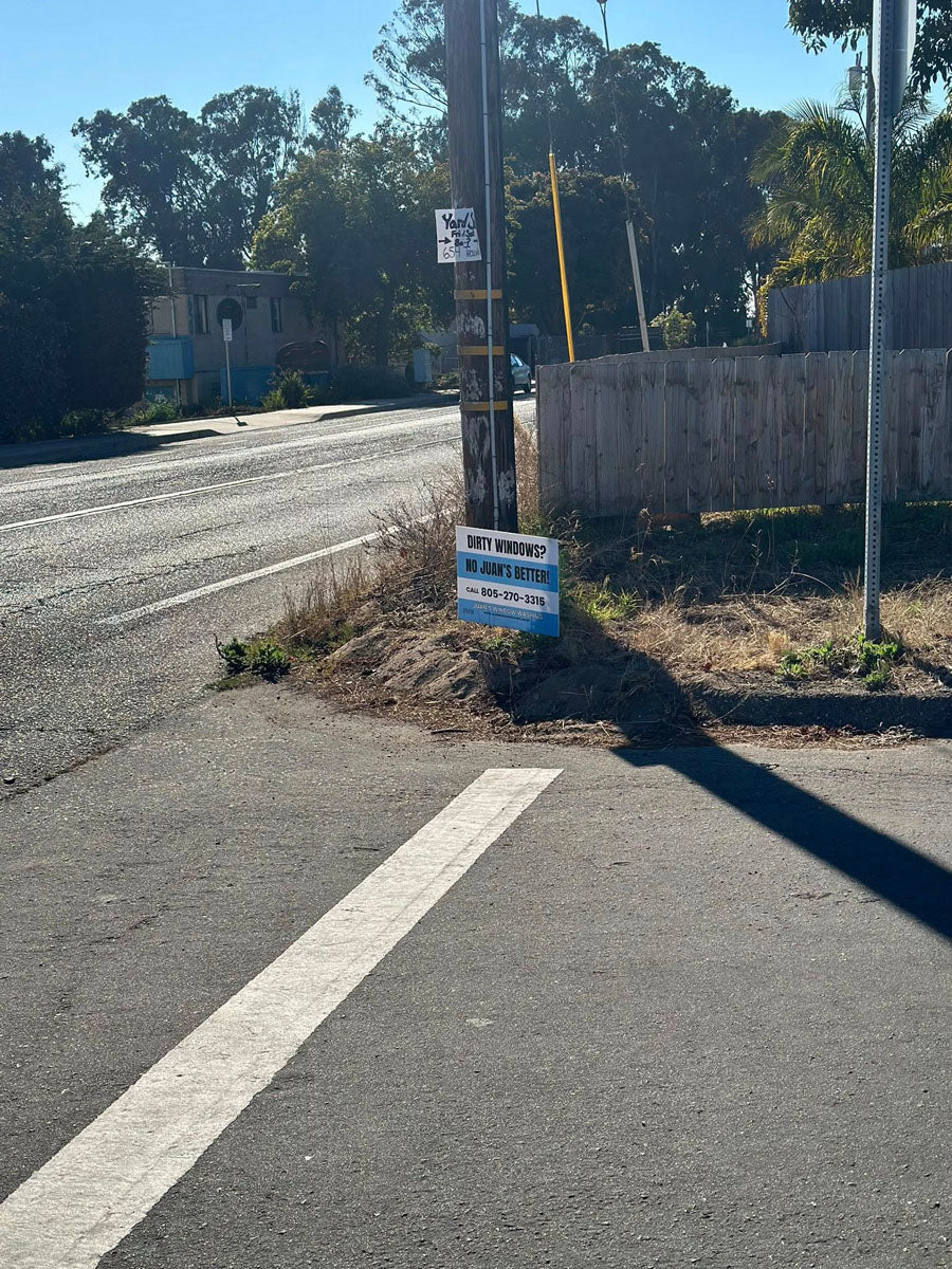 Dirty Windows yard sign for No Juan’s Better displayed on roadside pole near intersection, printed by WCR Marketing.