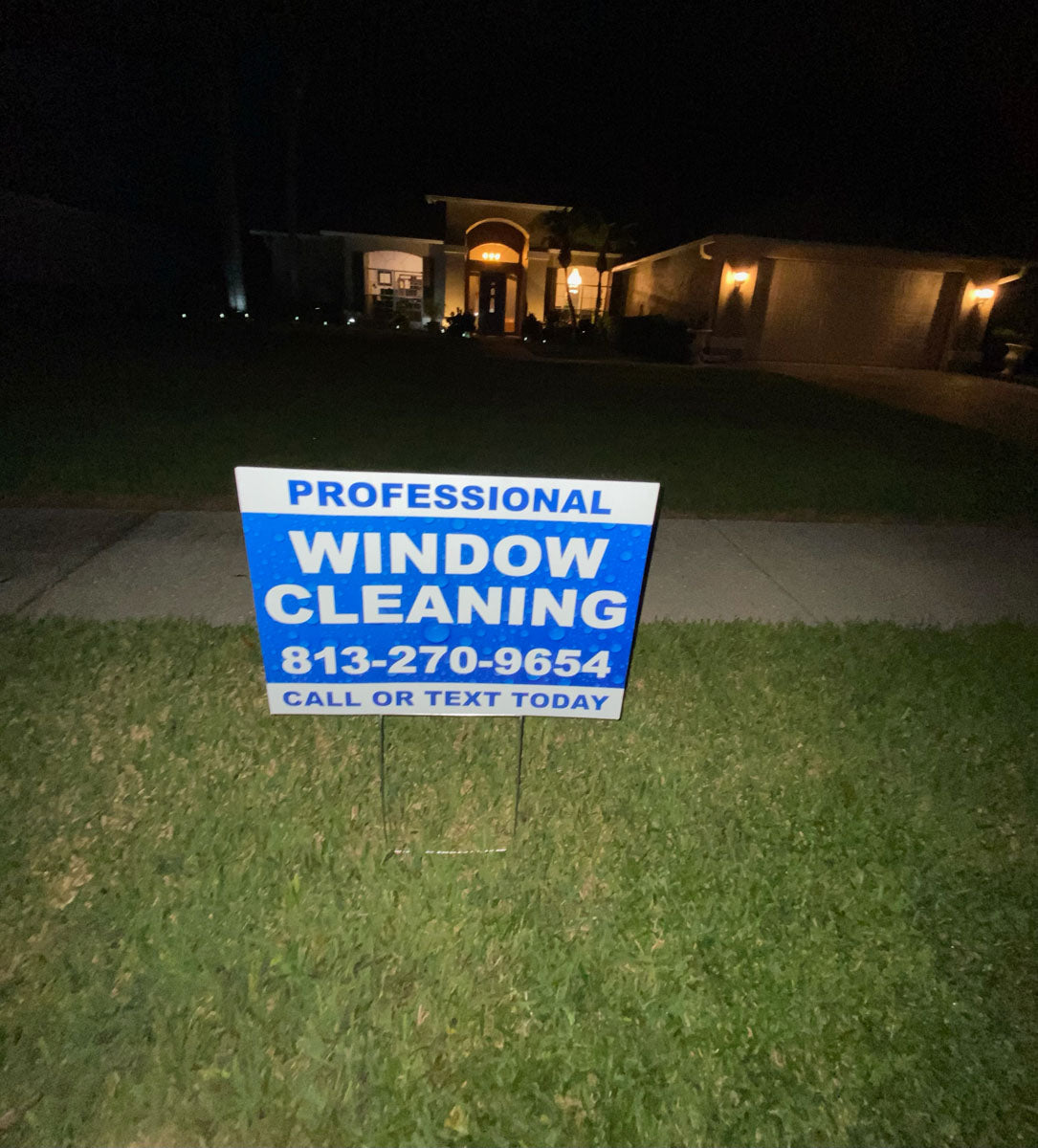 Professional Window Cleaning yard sign displayed at night in front of residential home, featuring blue bubble background and call or text message, printed by WCR Marketing.