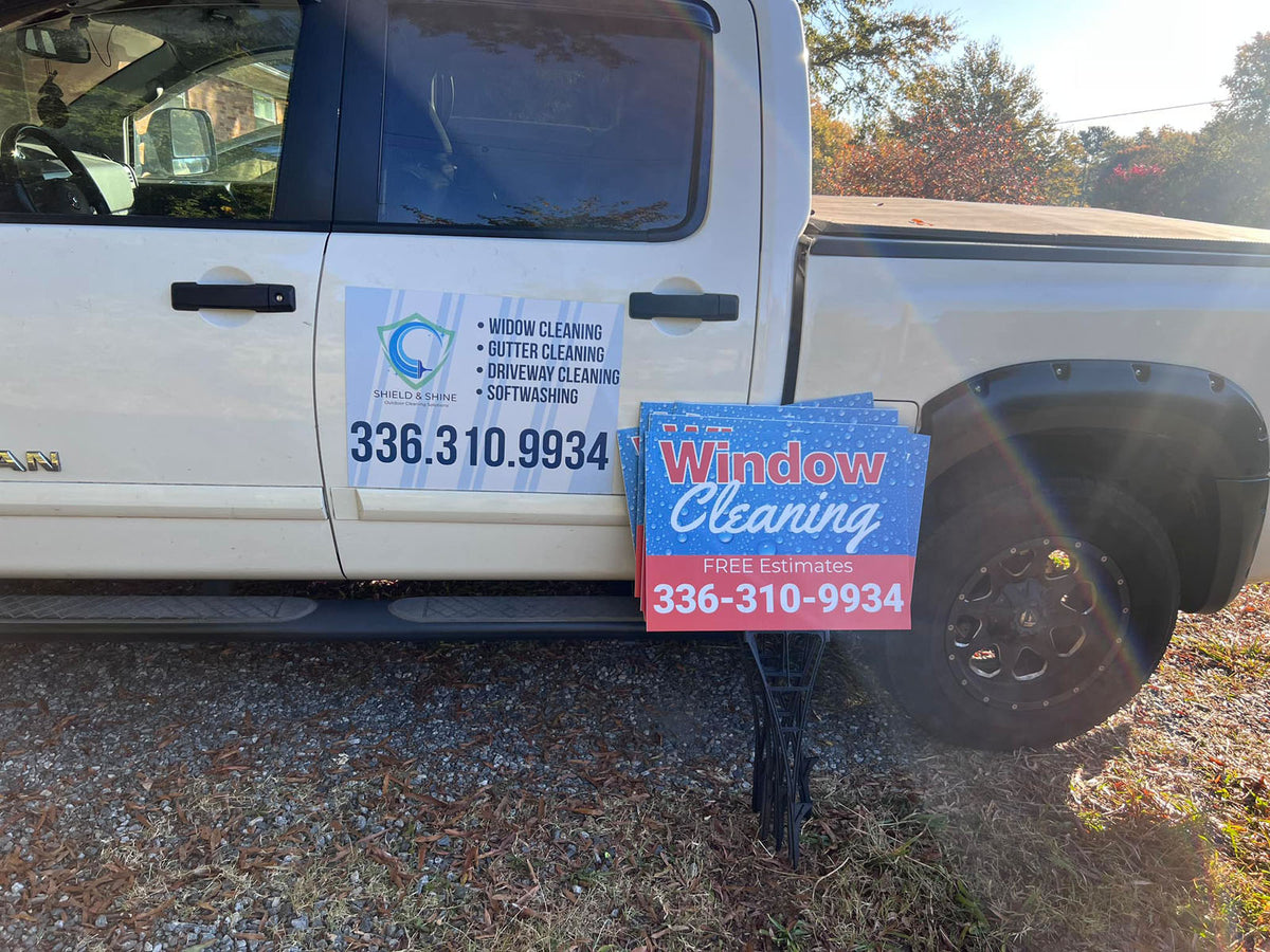 Shield & Shine yard sign promoting window cleaning, gutter cleaning, driveway cleaning, and soft washing displayed beside company truck, printed by WCR Marketing.