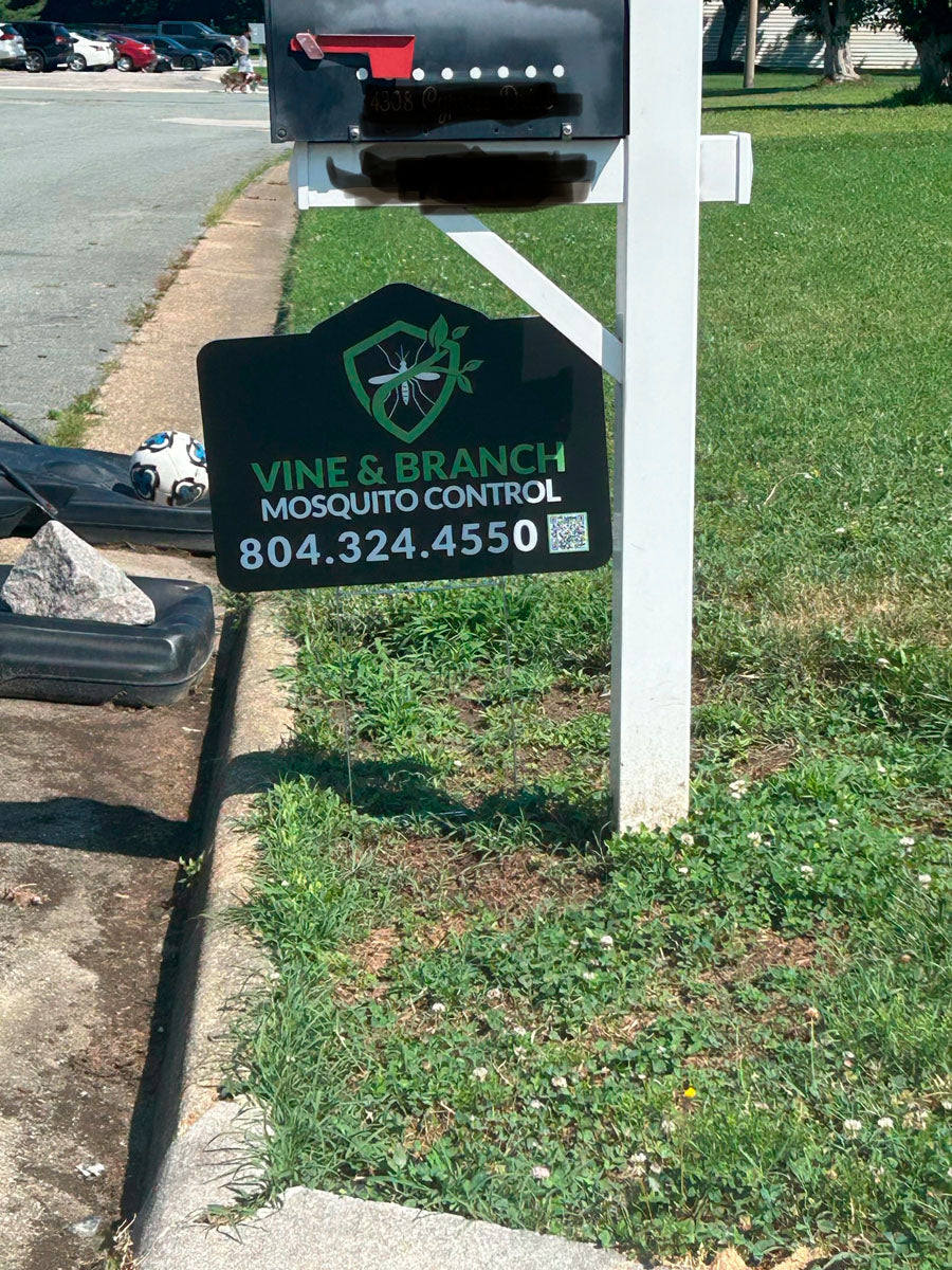 Die-cut mosquito control yard sign for Vine & Branch featuring shield and mosquito graphic displayed near mailbox, printed by WCR Marketing.