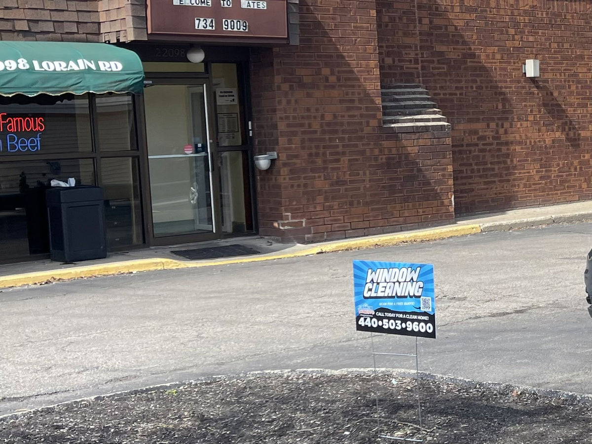 Window cleaning yard sign displayed outside a commercial brick building with call-to-clean message, printed by WCR Marketing.